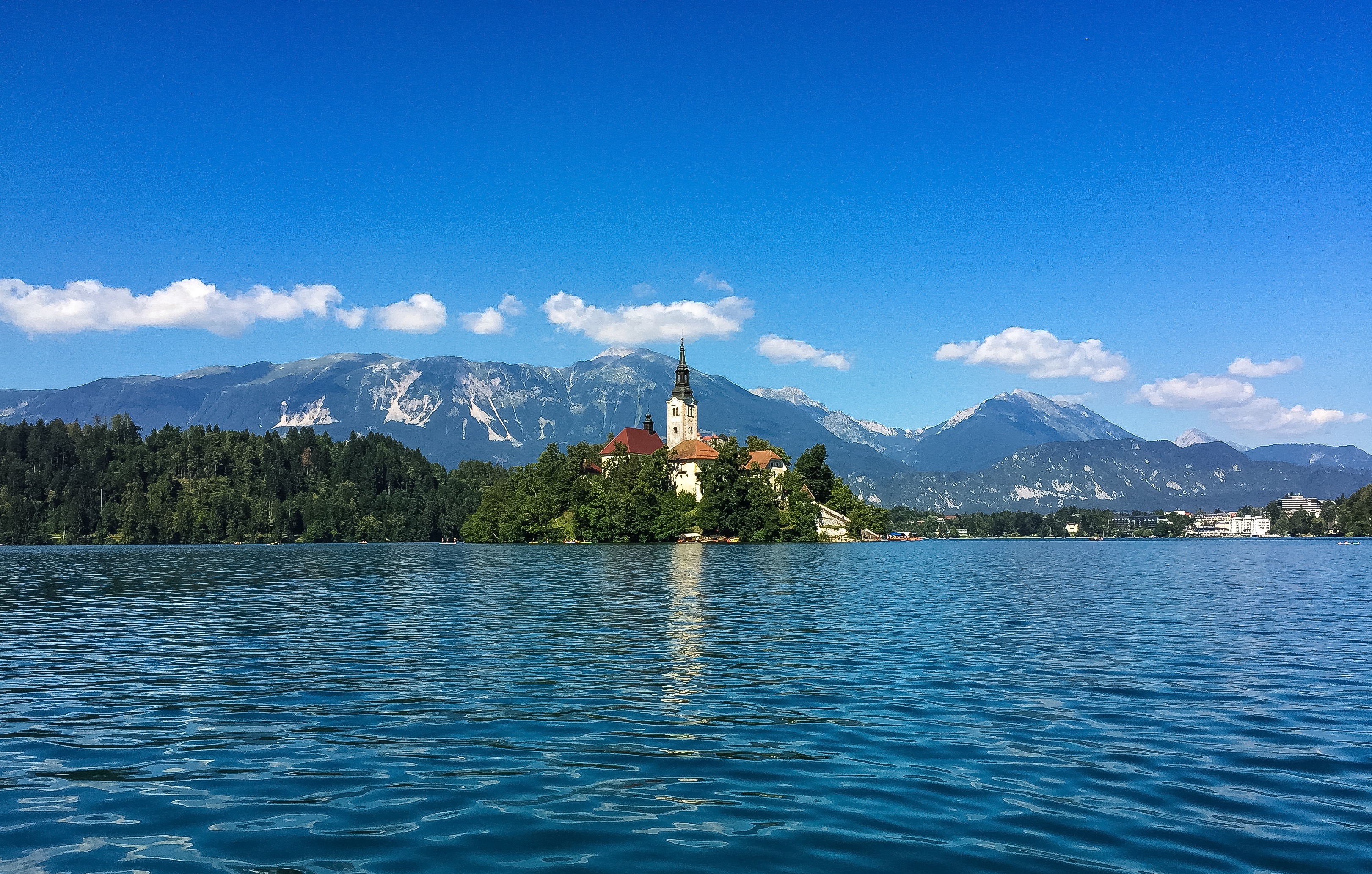 A lakeside view of an island church, with mountains in the distance